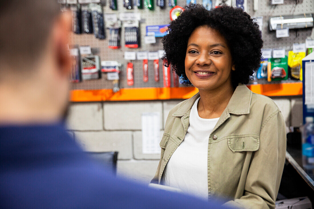 African American female hardware shop worker attending customer at store