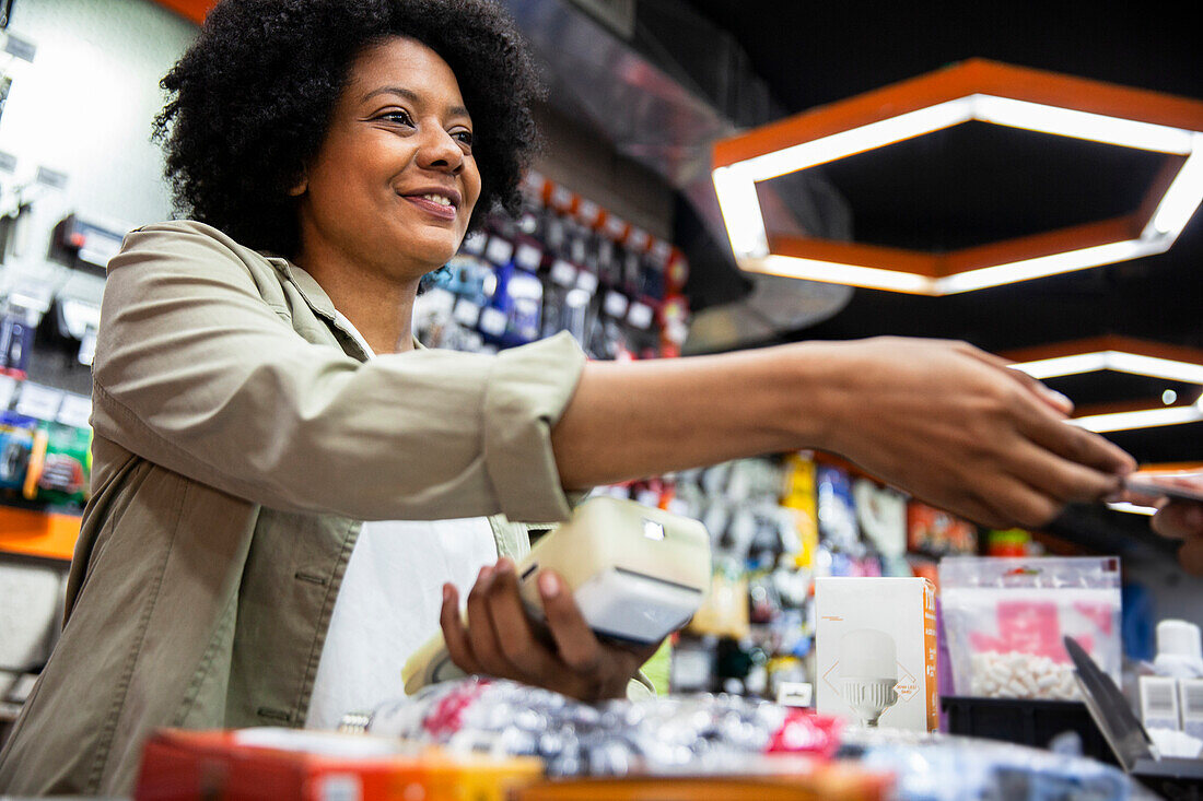 Eine afroamerikanische Eisenwarenverkäuferin belastet eine Kreditkarte eines Kunden
