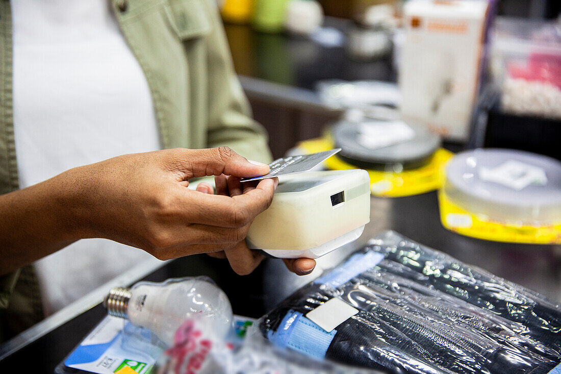 African American hardware shop worker processing credit card payment