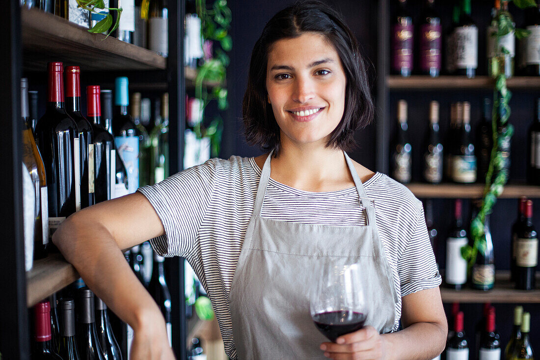 Female sommelier holding glass of wine while looking at the camera