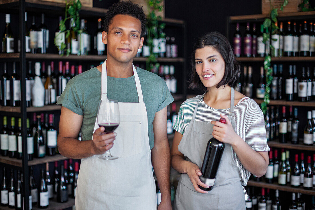 Latin American liquor store coworkers holding bottle of red wine