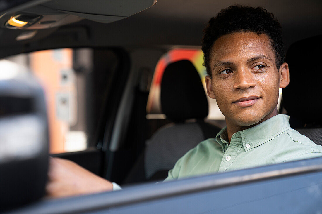 Mittelaufnahme eines gut aussehenden afroamerikanischen Geschäftsmannes in seinem Auto auf dem Weg in sein Büro