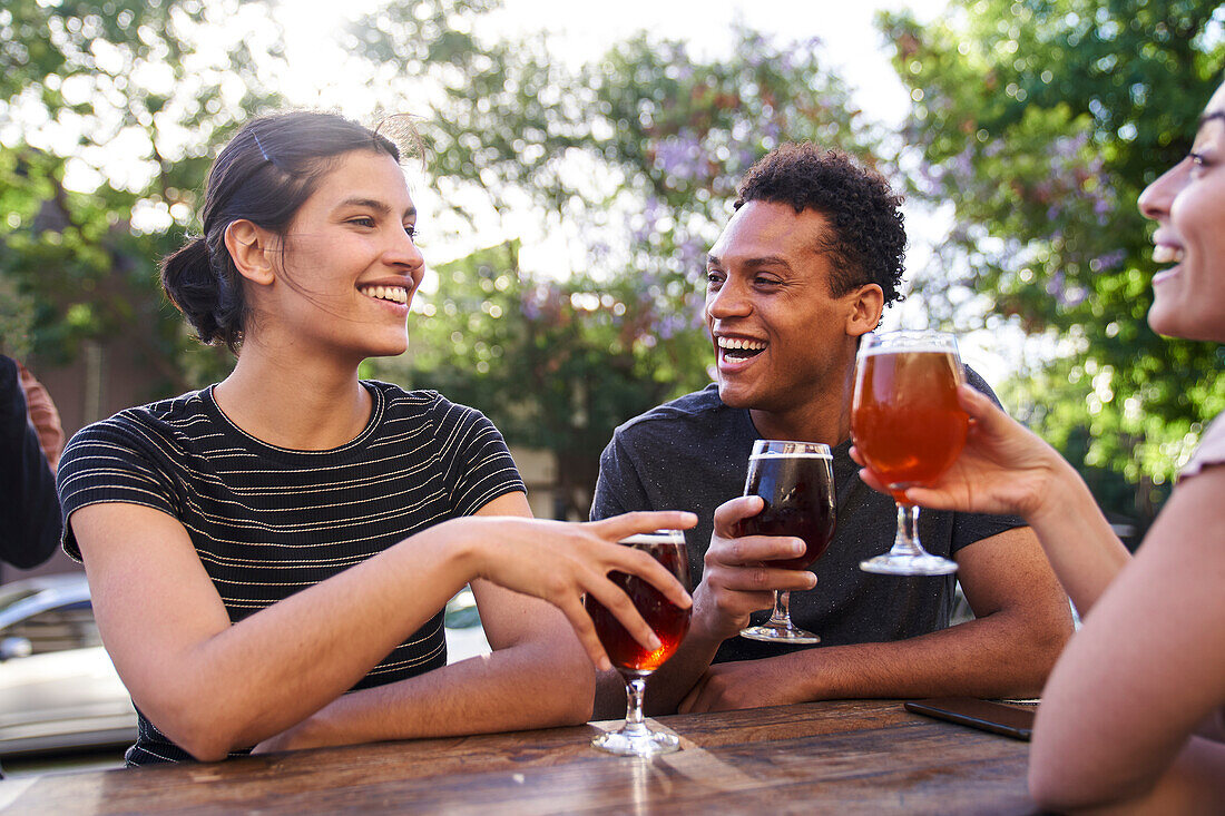 Mittlere Einstellung einer jungen lateinamerikanischen Frau und ihrer Gruppe von Freunden beim Genuss von Craft Beer