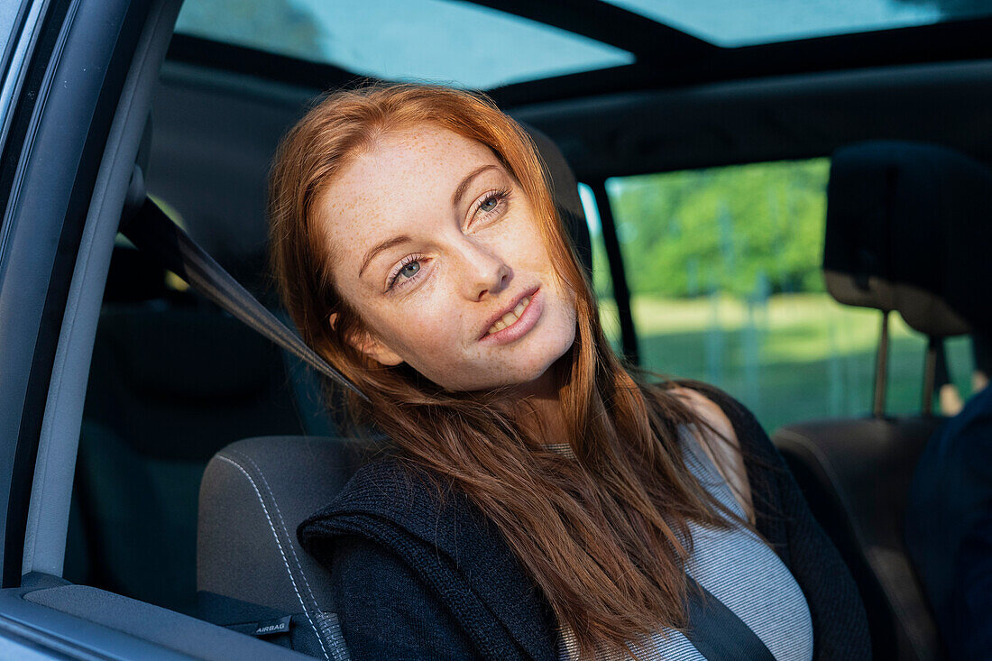 Lächelnde junge Frau im Auto sitzend