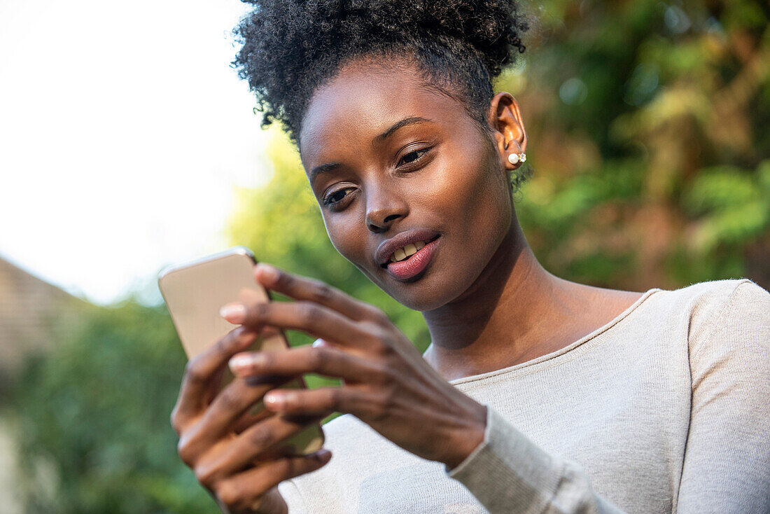 Close-up of smiling young woman using smartphone in park