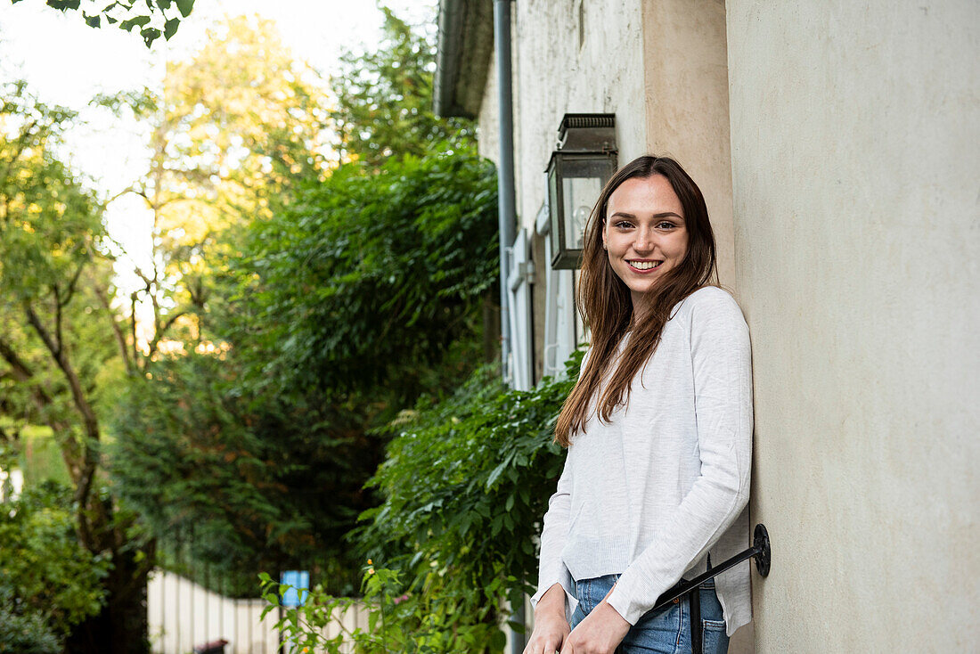 Porträt einer lächelnden jungen Frau, die vor der Tür steht