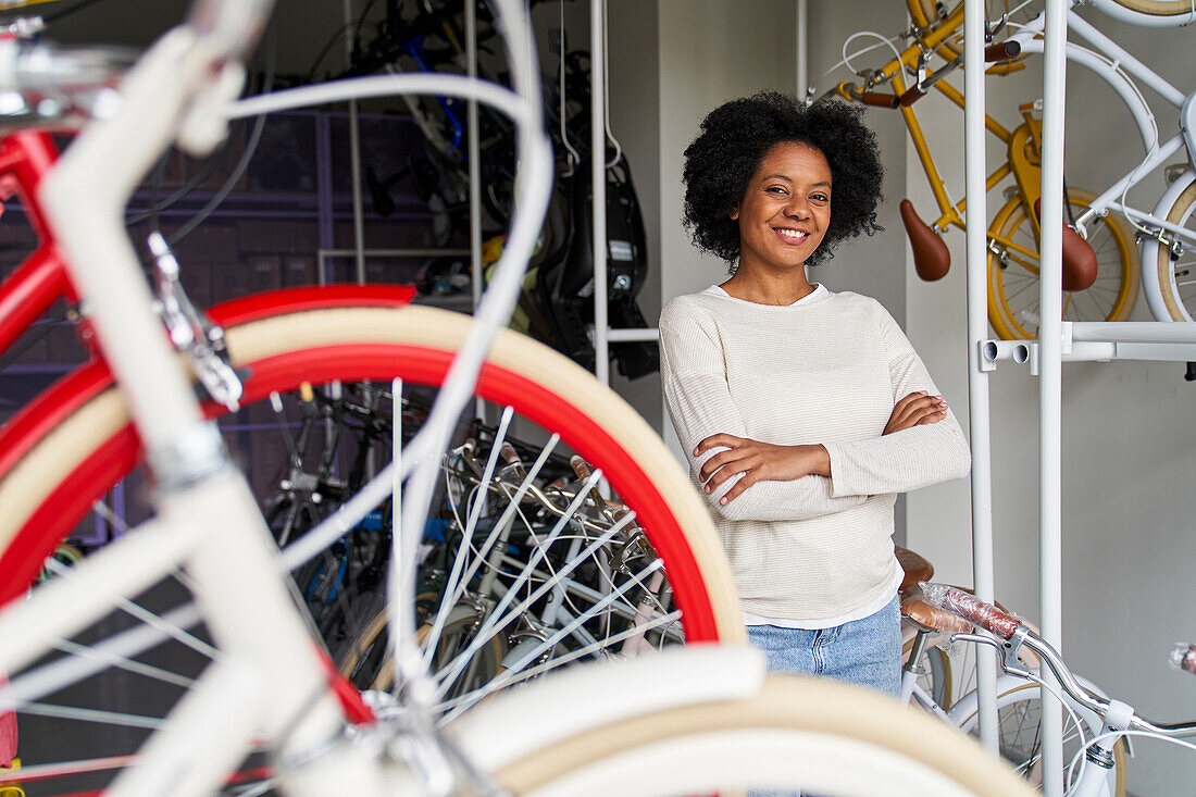 Mittlere Einstellung einer afroamerikanischen Fahrradladenbesitzerin in ihrem Geschäft mit Fahrrädern im Vordergrund