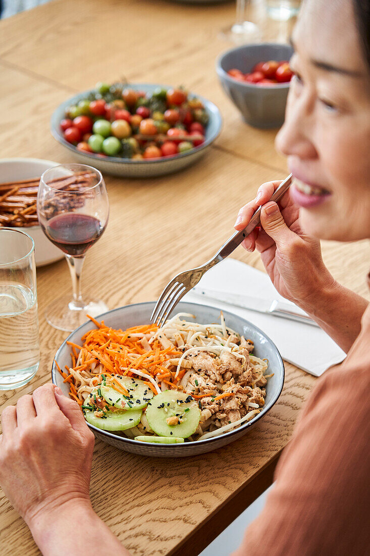 Seitenansicht einer asiatisch-amerikanischen Frau, die mit Freunden isst
