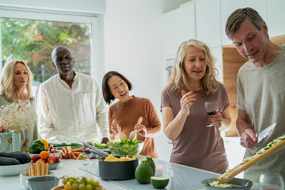 Diverse group of senior friends gathered at kitchen while cooking