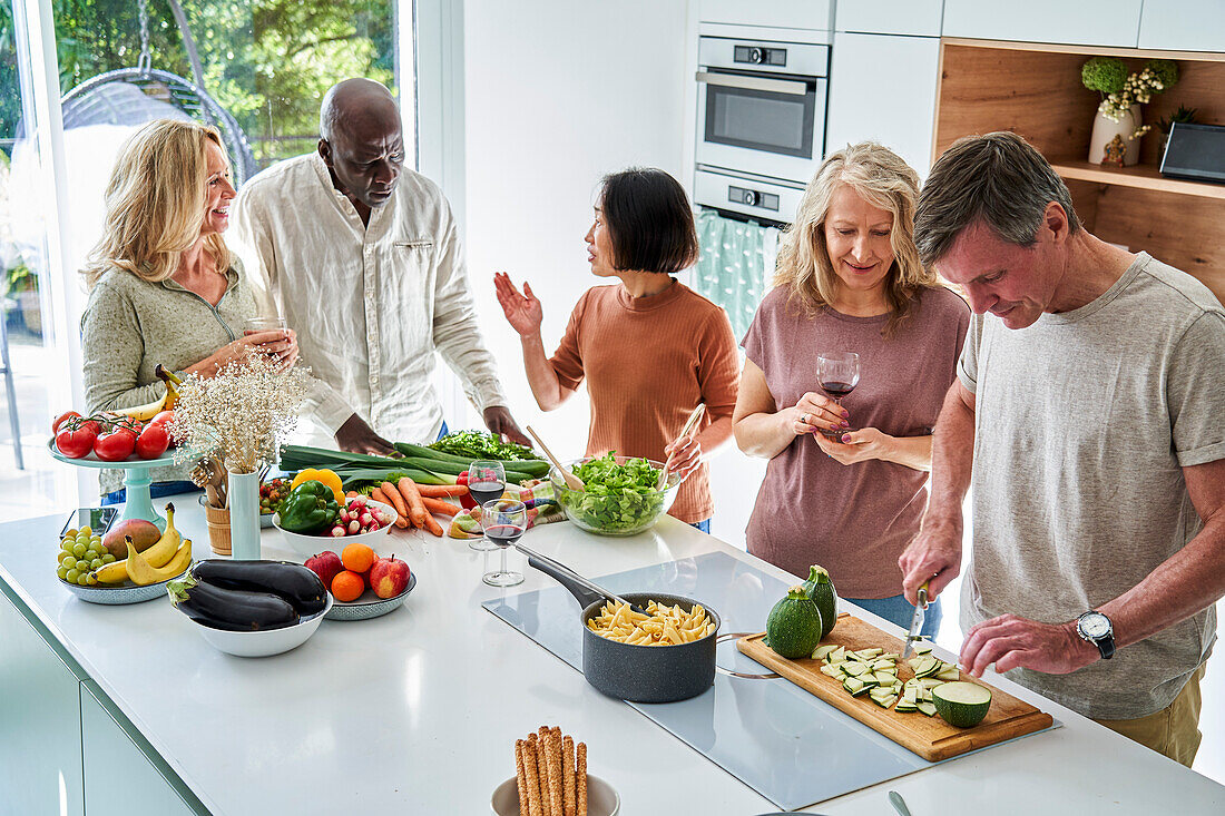 Gruppe von Seniorenfreunden in der Küche bei der Zubereitung des Abendessens
