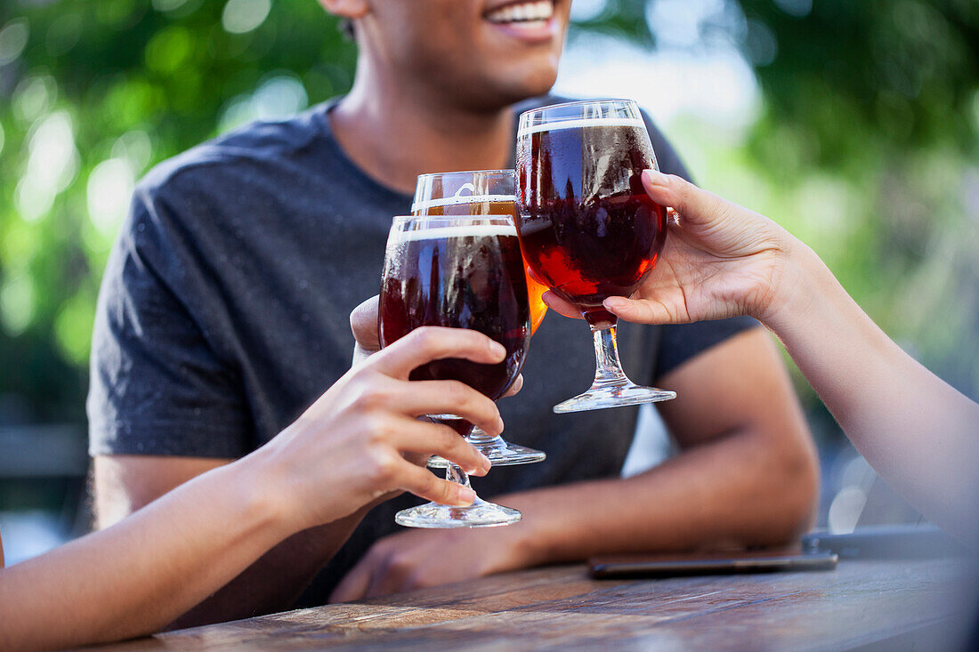 Mittelaufnahme von drei Freunden, die mit Bier anstoßen