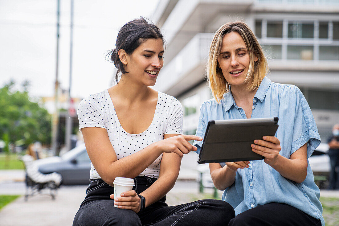 Front view shot of two female digital nomads working outdoors