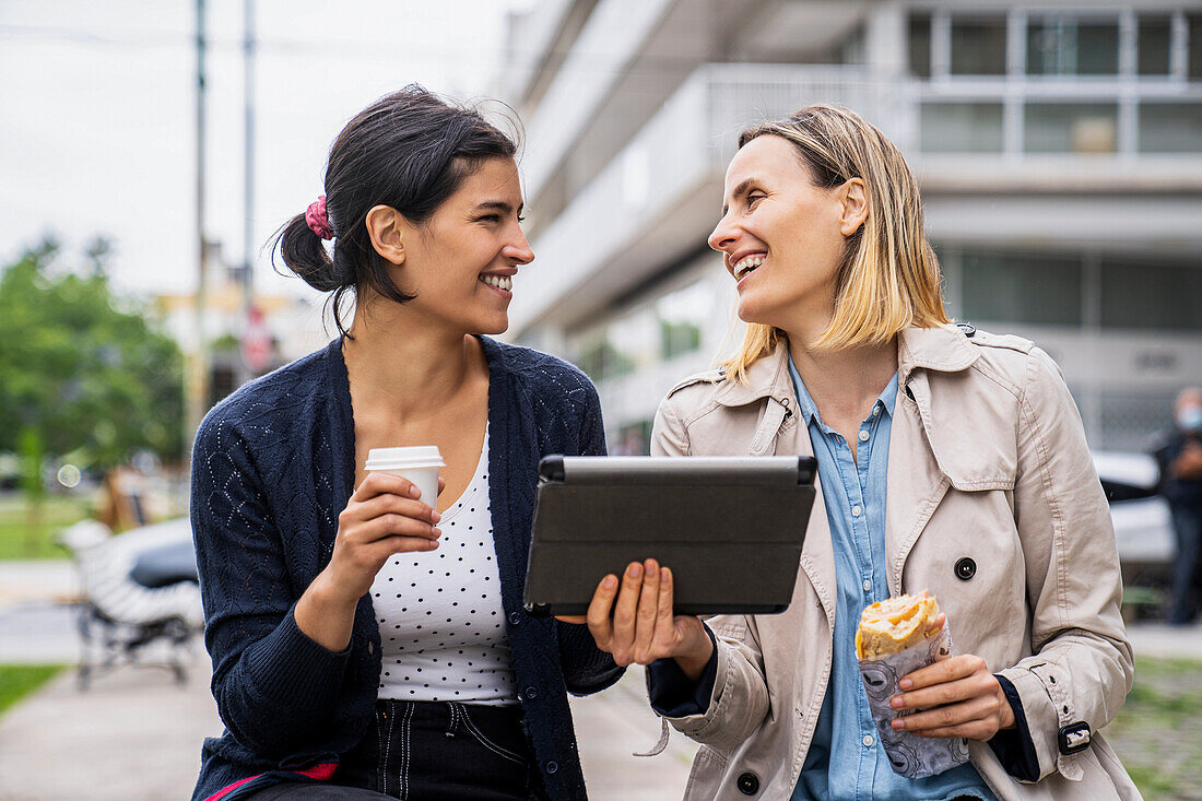 Front view shot of two female digital nomads working outdoors and having a good time