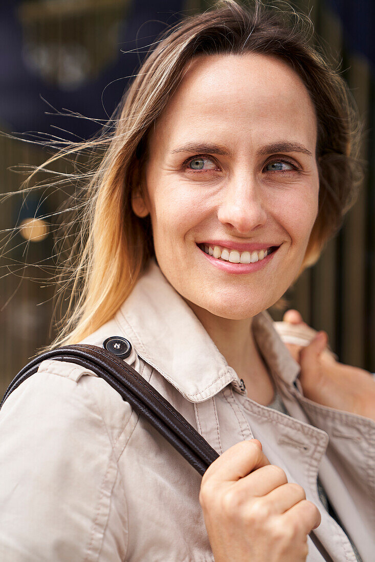 Mid-shot of smiling lady with handbag looking into the distance