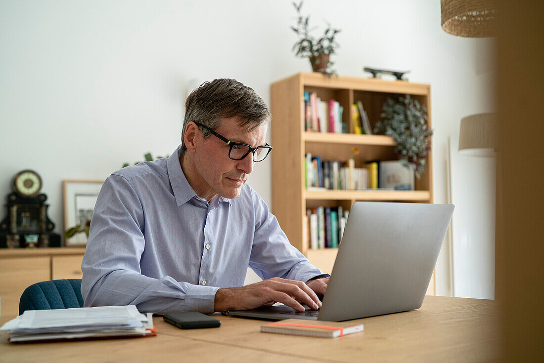 Älterer Geschäftsmann bei der Arbeit zu Hause am Laptop