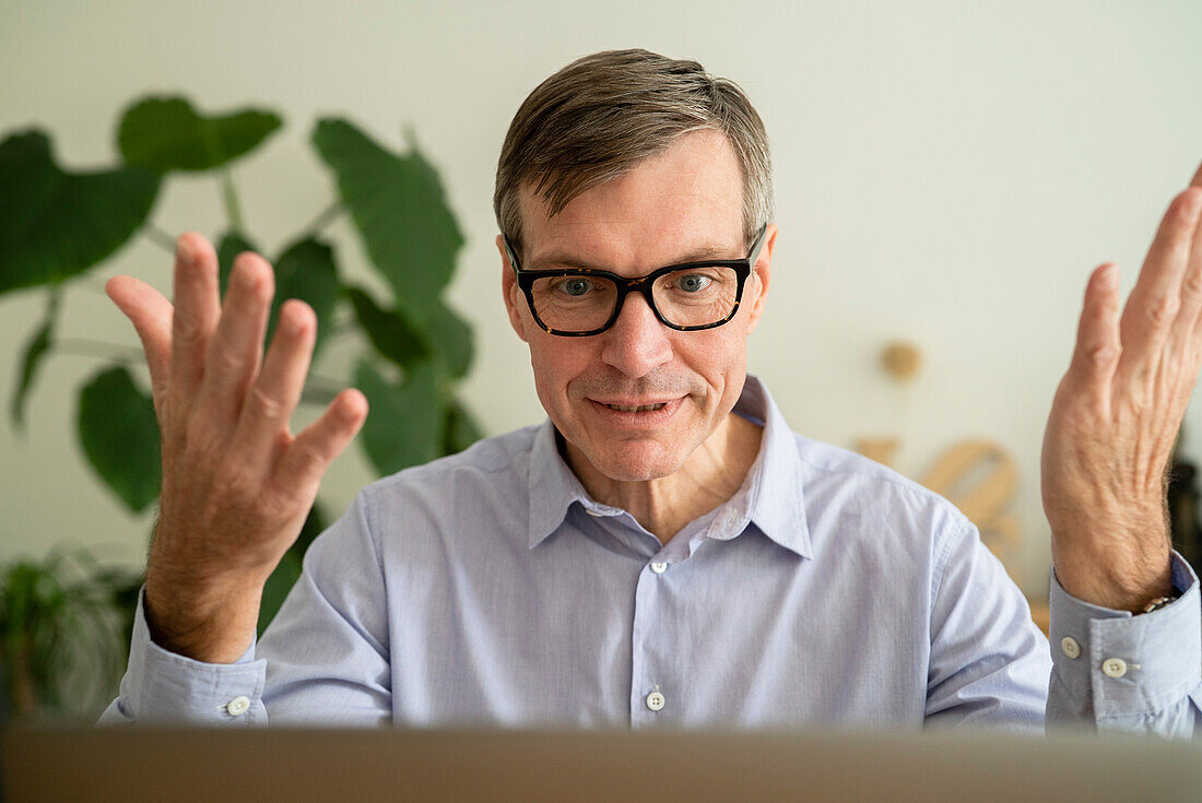 Älterer Mann, der zu Hause an seinem Laptop eine Online-Sitzung abhält