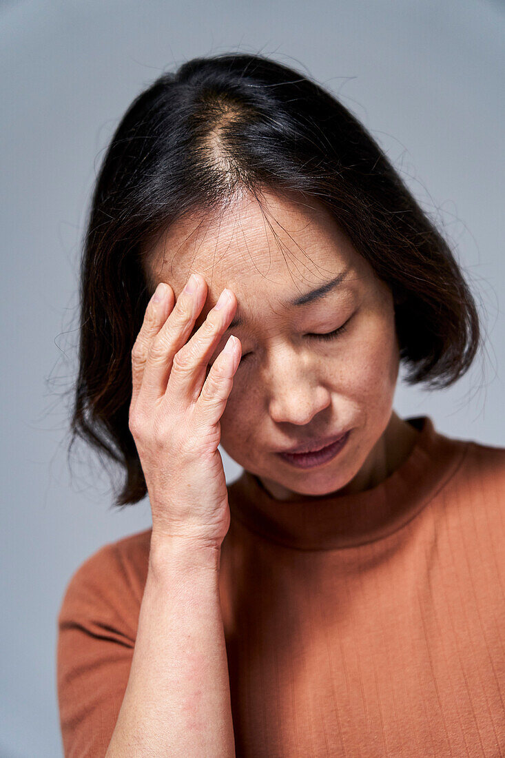 Mature Asian woman having a headache