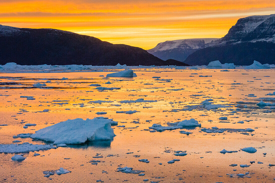 Grönland, Scoresby Sund, Gasefjord. Sonnenuntergang mit Eisbergen und Blitzeis.