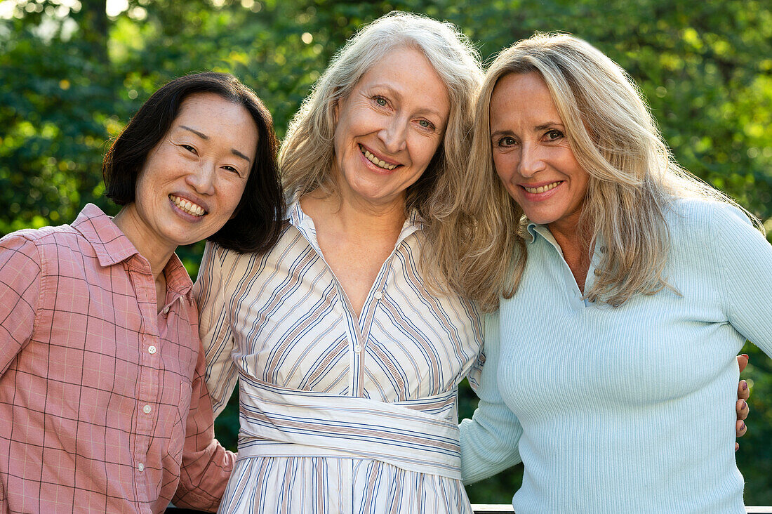 Drei ältere Frauen posieren zusammen für ein Gruppenfoto im Freien