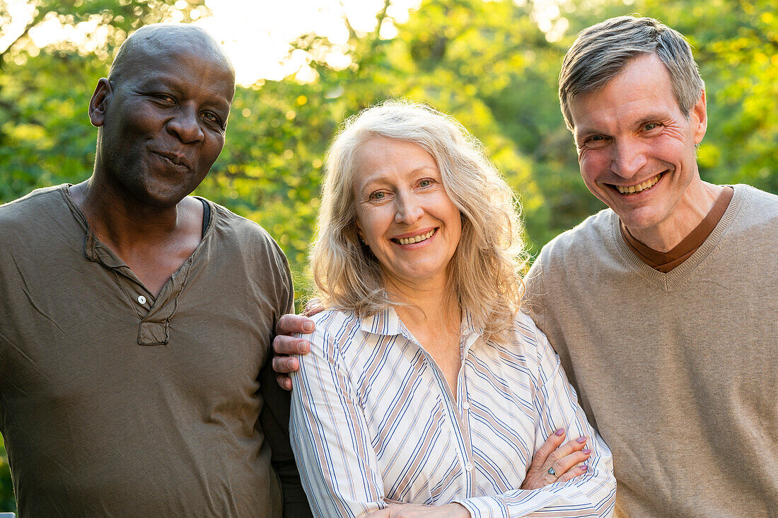 Senior lady posing with her two male friends while hanging out in her backyard at sunset