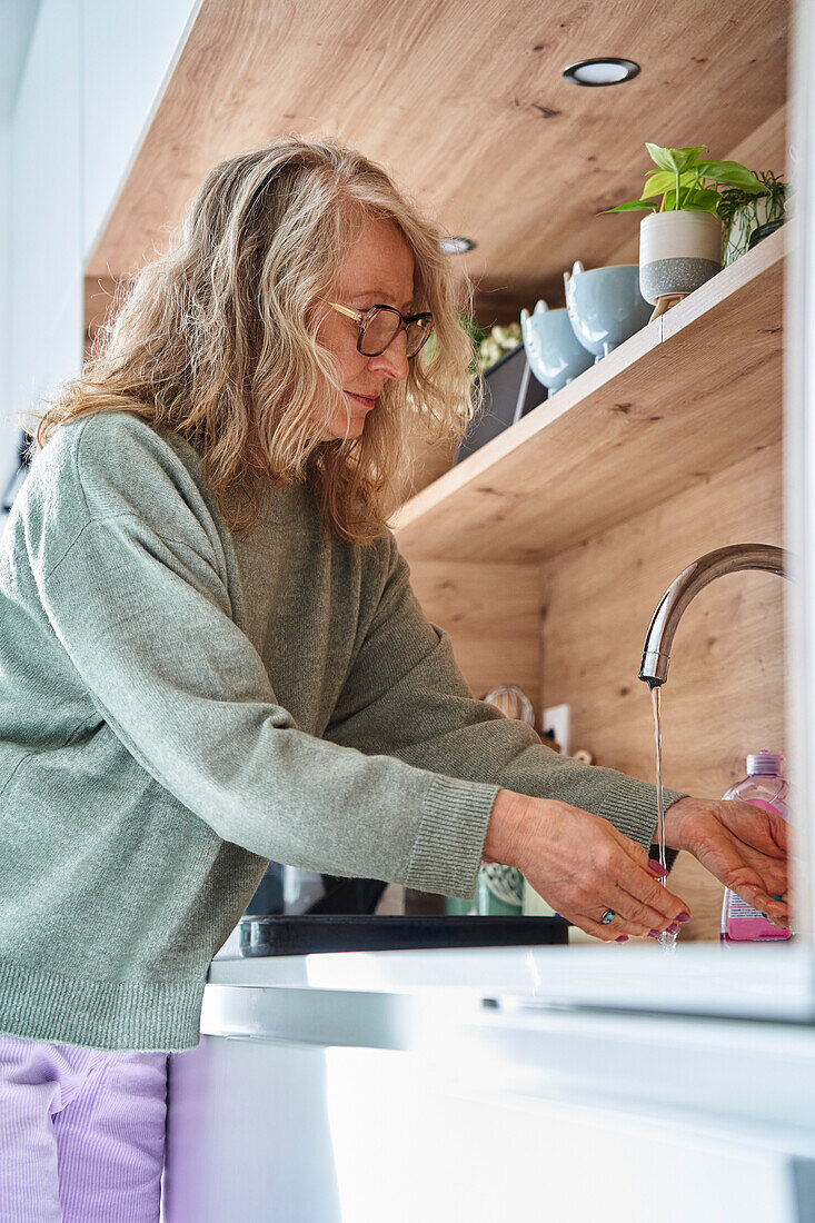 Ältere Frau wäscht in der Küche ab