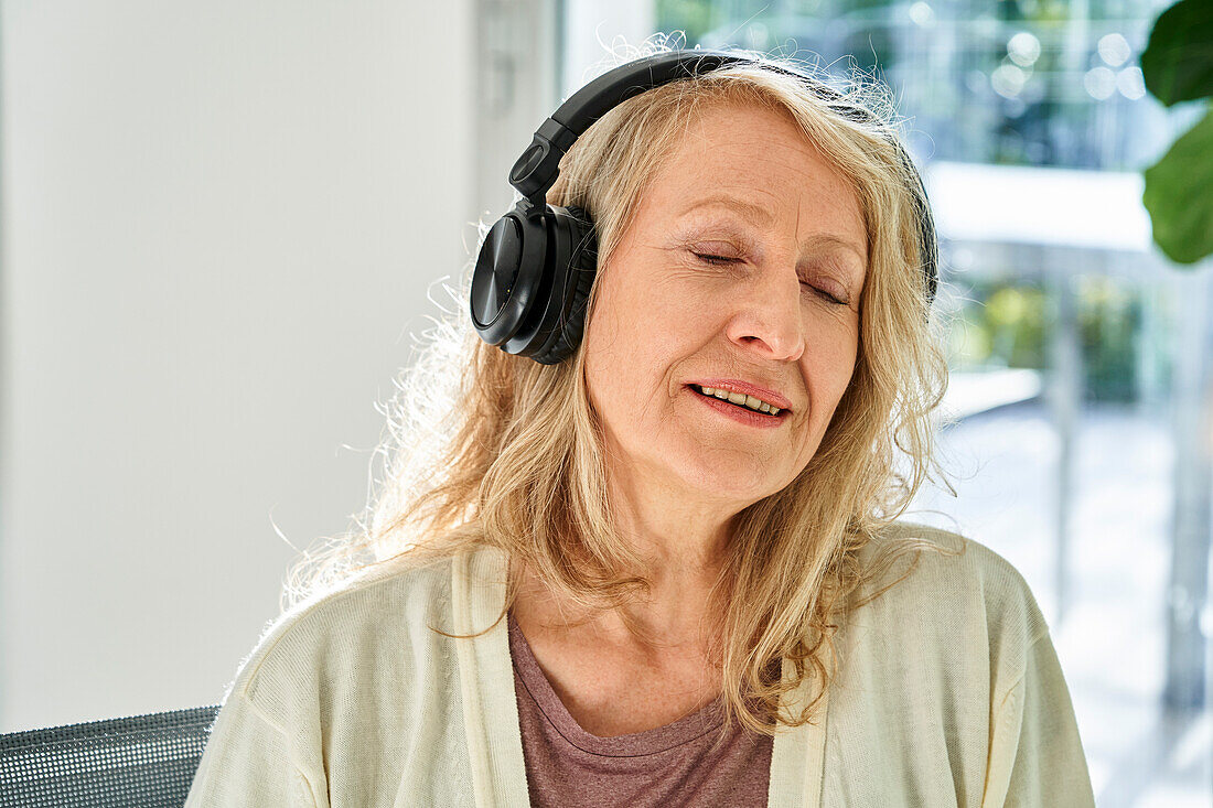 Senior woman enjoying listening to music on headphones