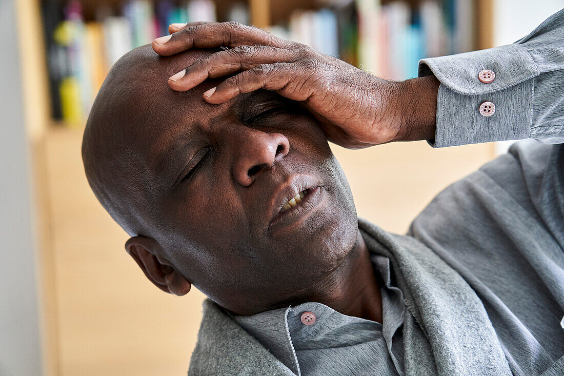 Middle age African-American man holding his head in pain