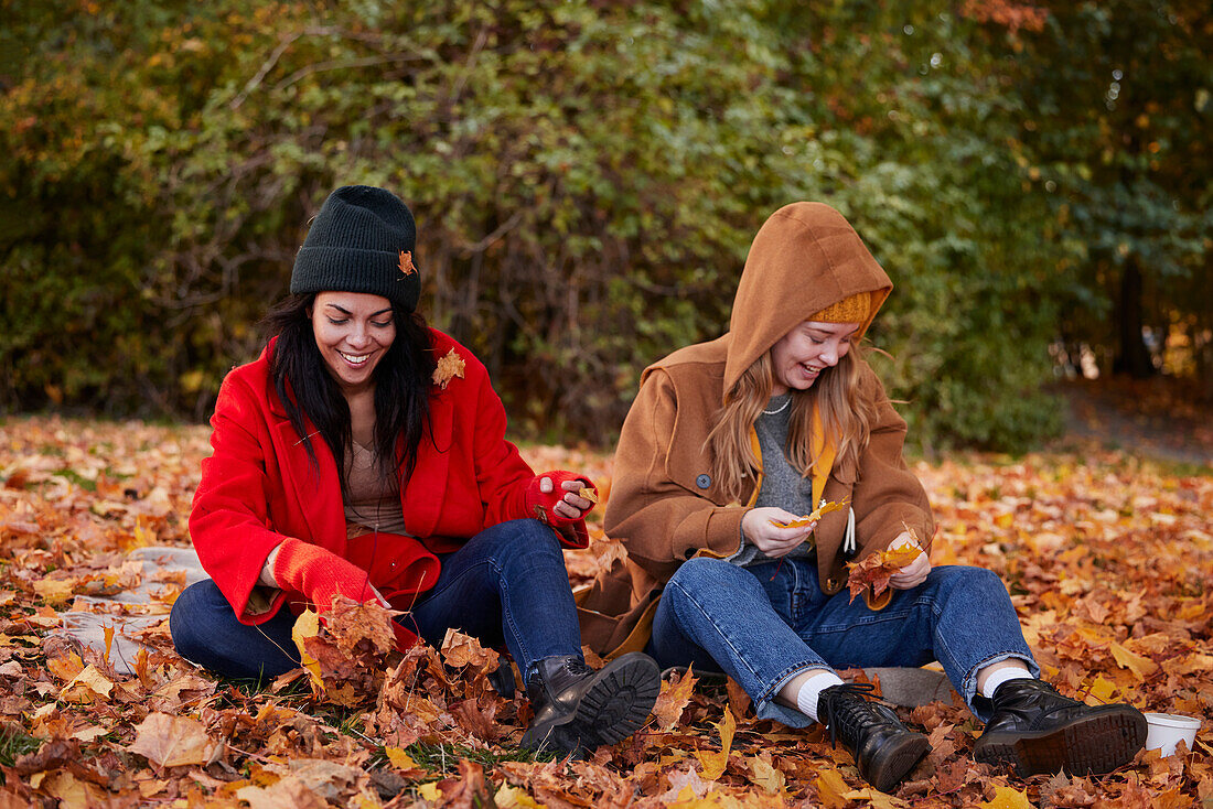 Freunde spielen mit Herbstblättern im Park