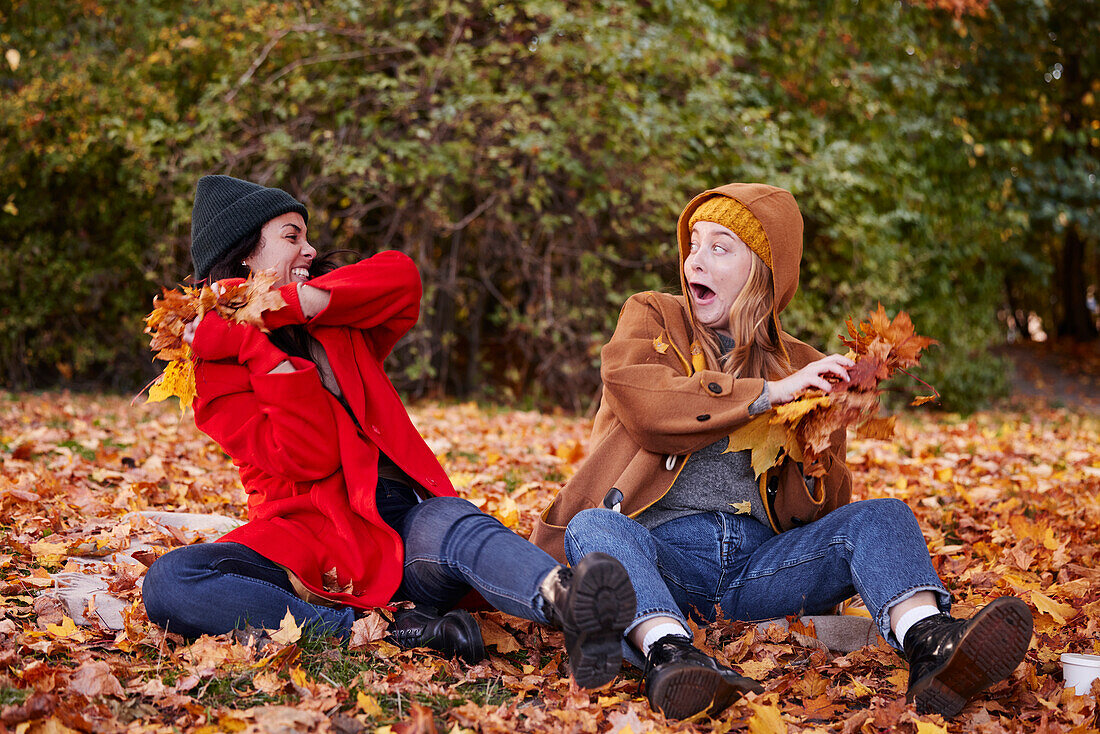 Friends playing with autumn leaves in park