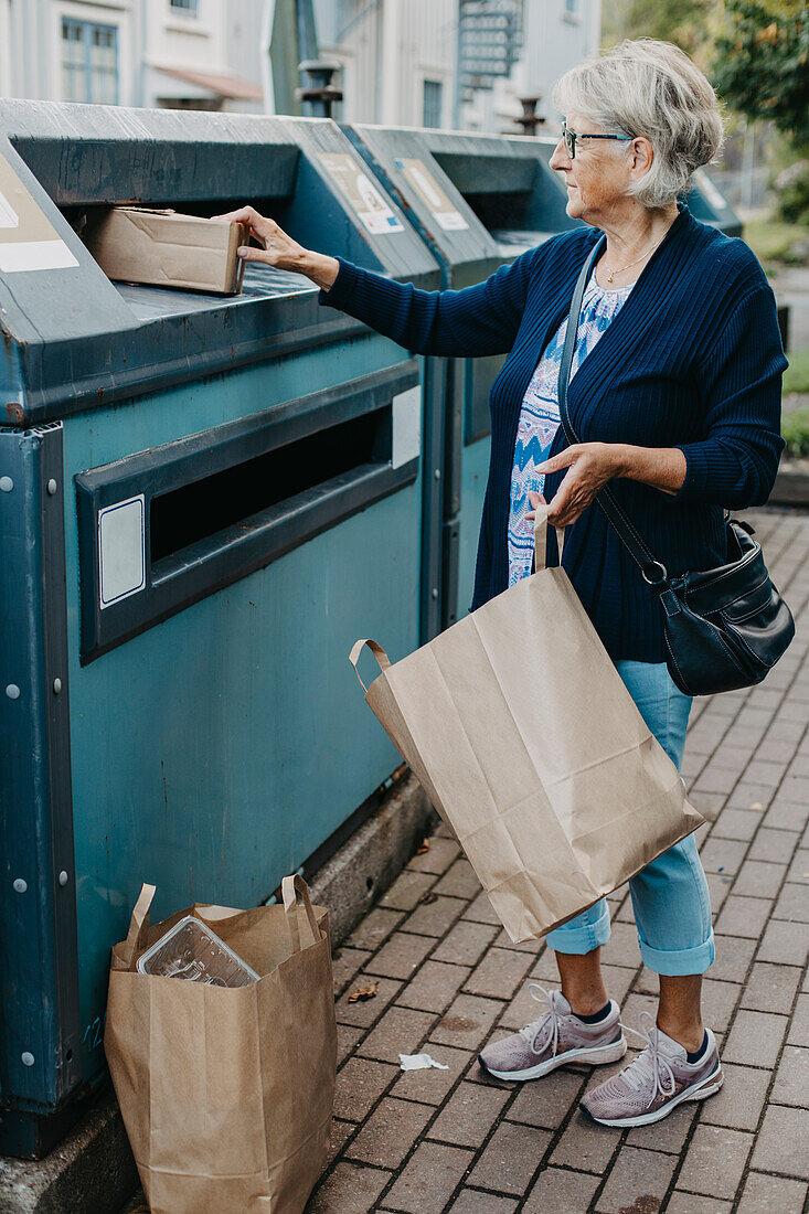 Woman putting cardboard in recycling bin