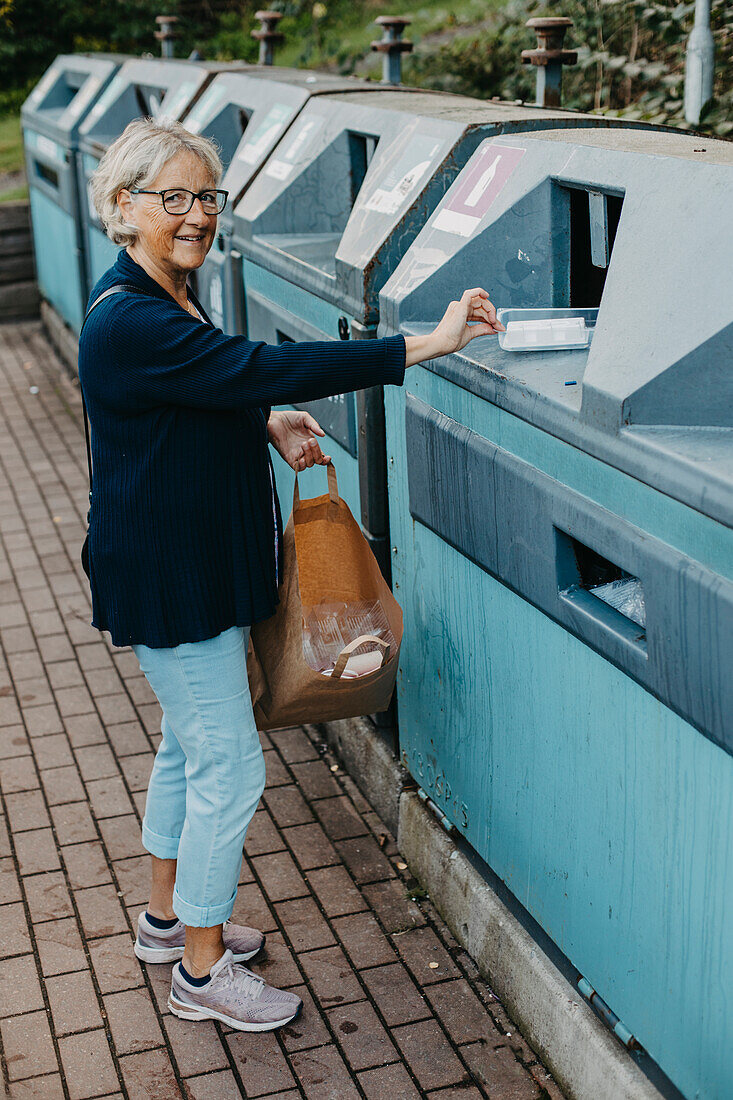 Frau wirft Plastik in die Wertstofftonne