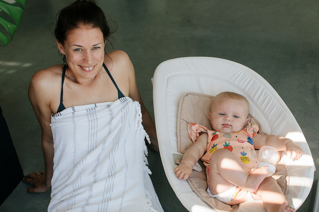 Smiling woman relaxing with baby daughter