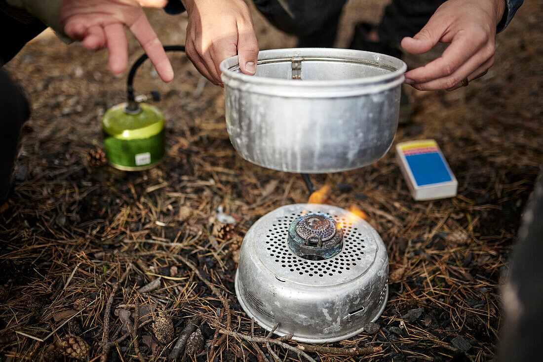 Person putting pot on camping stove