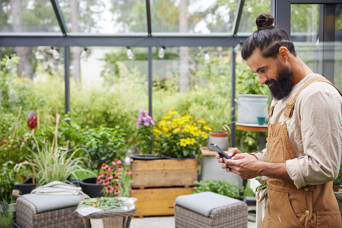 Man in greenhouse using cell phone