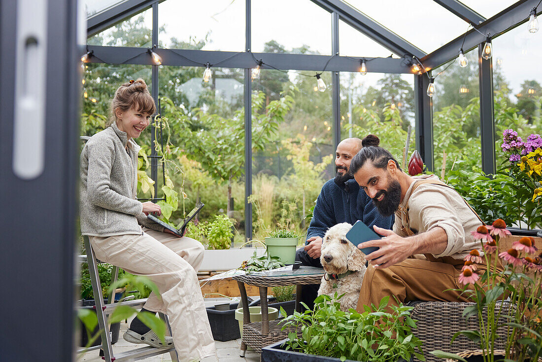 Smiling friends sitting in greenhouse