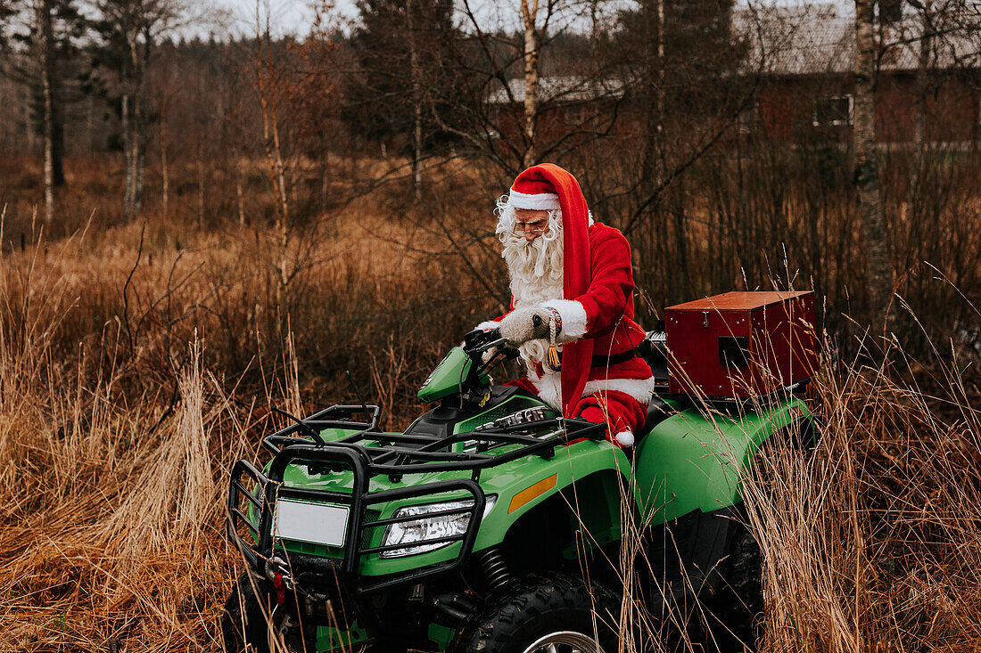 Mann im Weihnachtsmannkostüm fährt Rasenmäher
