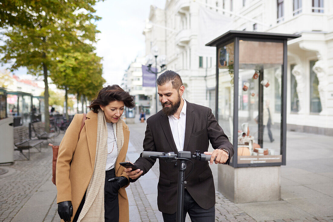 Colleagues walking in city and using phone