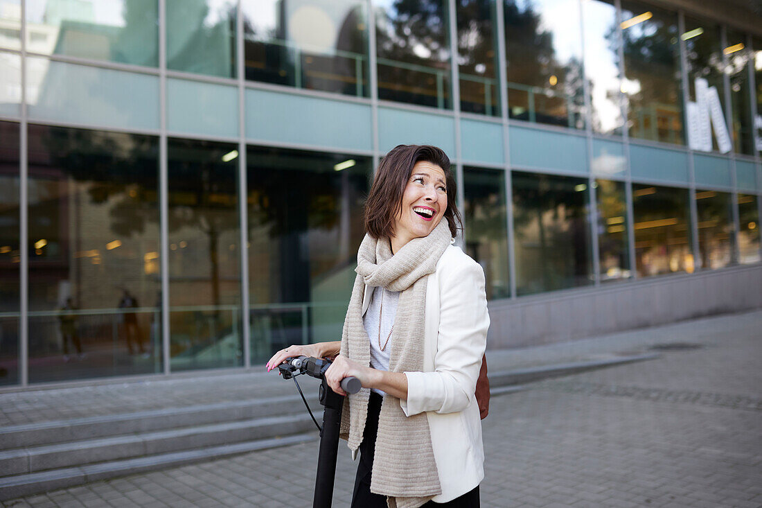 Smiling businesswoman using electric push scooter