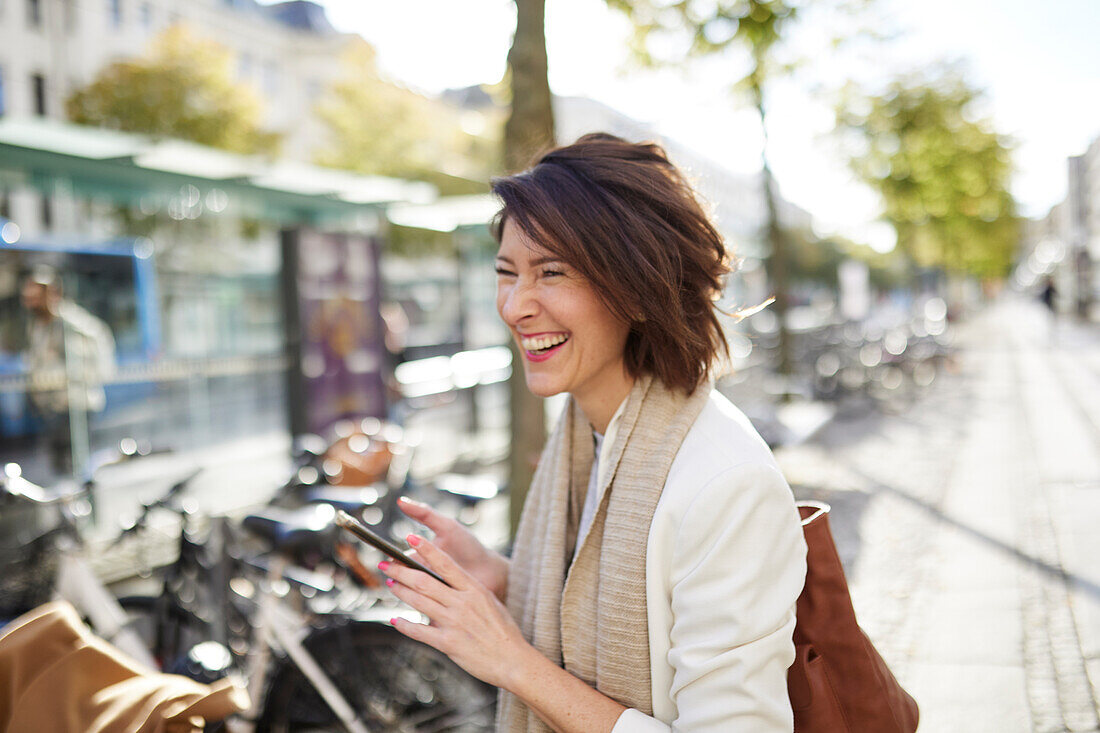 Smiling businesswoman using smart phone in street