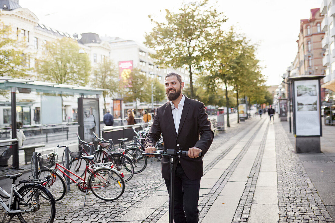 Businessman riding electric push scooter in city