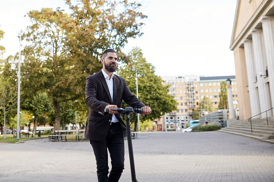 Businessman riding electric push scooter