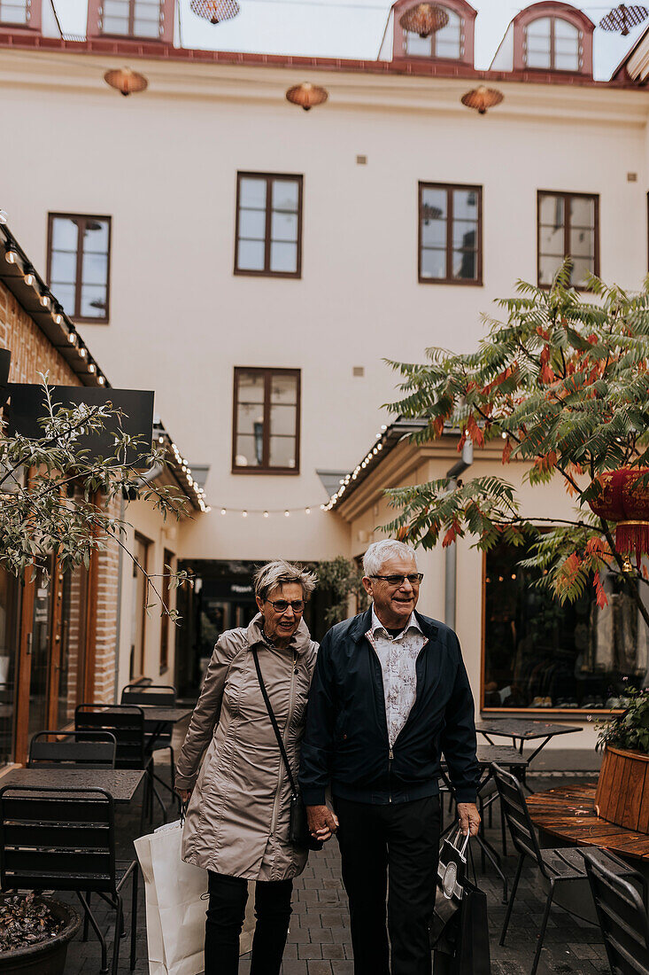 Senior couple with shopping bags walking by restaurant