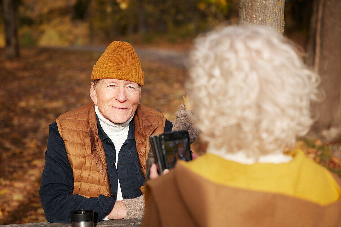 Ältere Frau fotografiert ihren Partner im Park