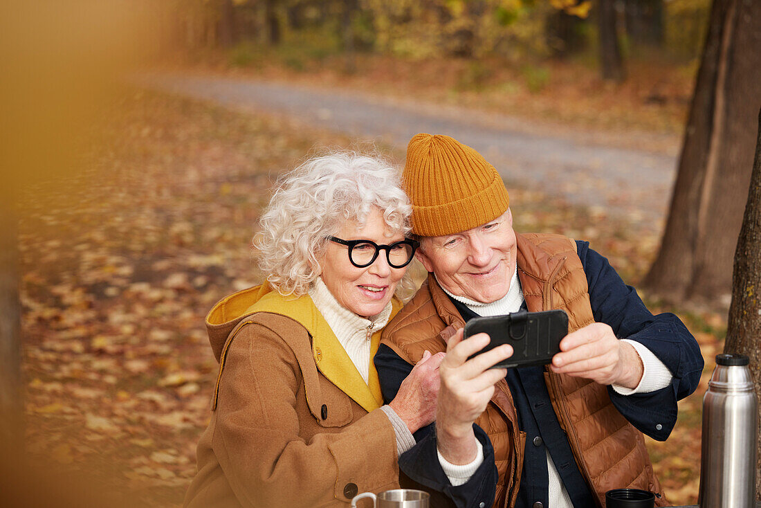 Senior couple taking selfie in park