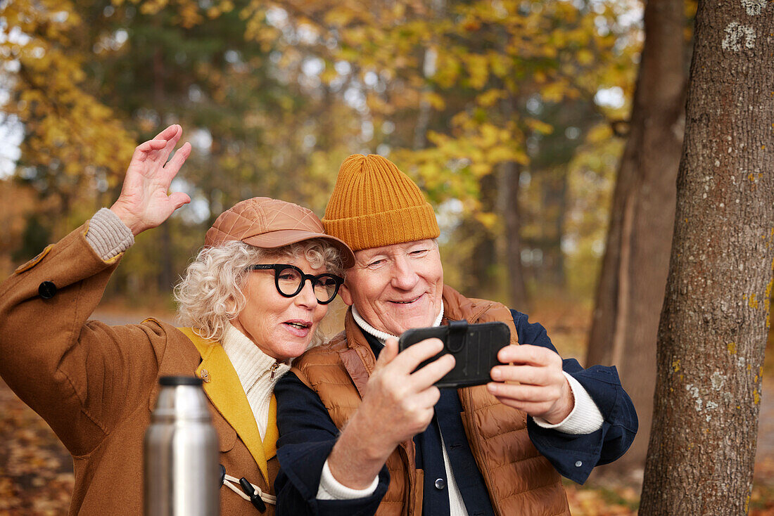 Senior couple taking selfie in park