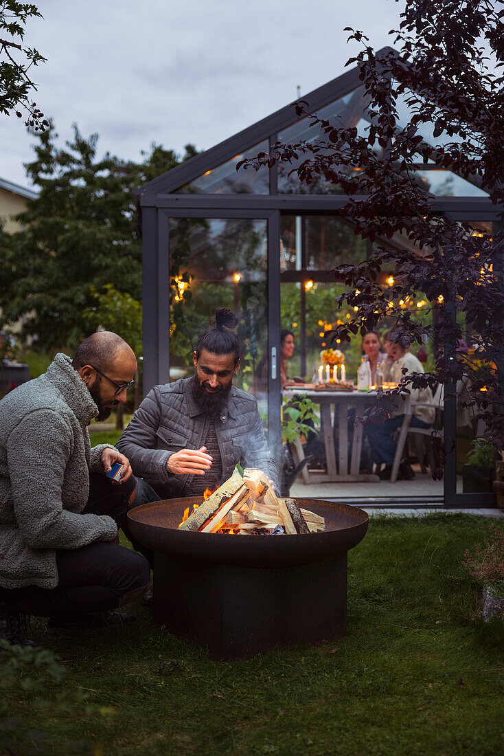 Male friends preparing fire in garden