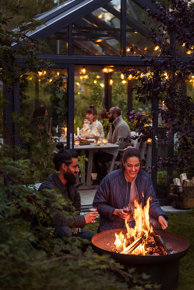 Freunde sitzen am Feuer im Garten