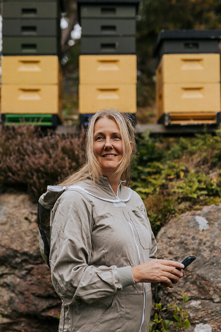 Imker in der Nähe des Bienenstocks stehend