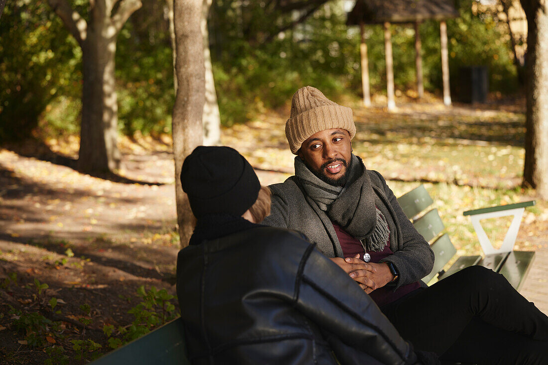 Smiling man talking to friend on bench