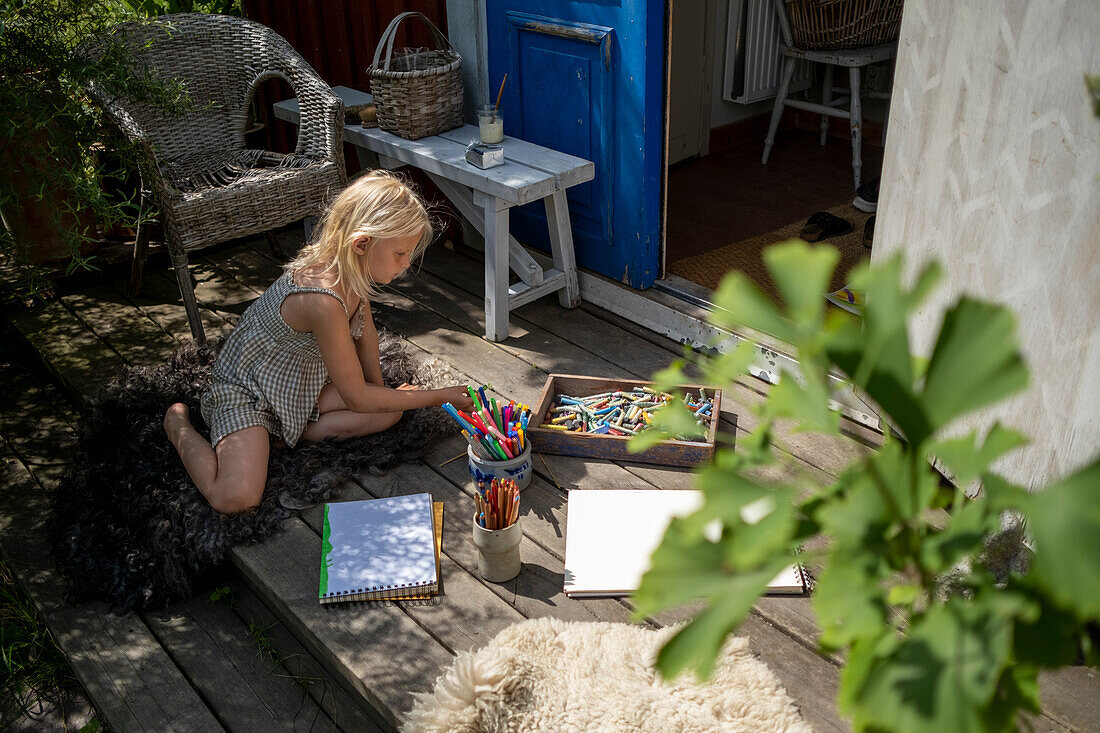 Girl drawing in front of wooden holiday house